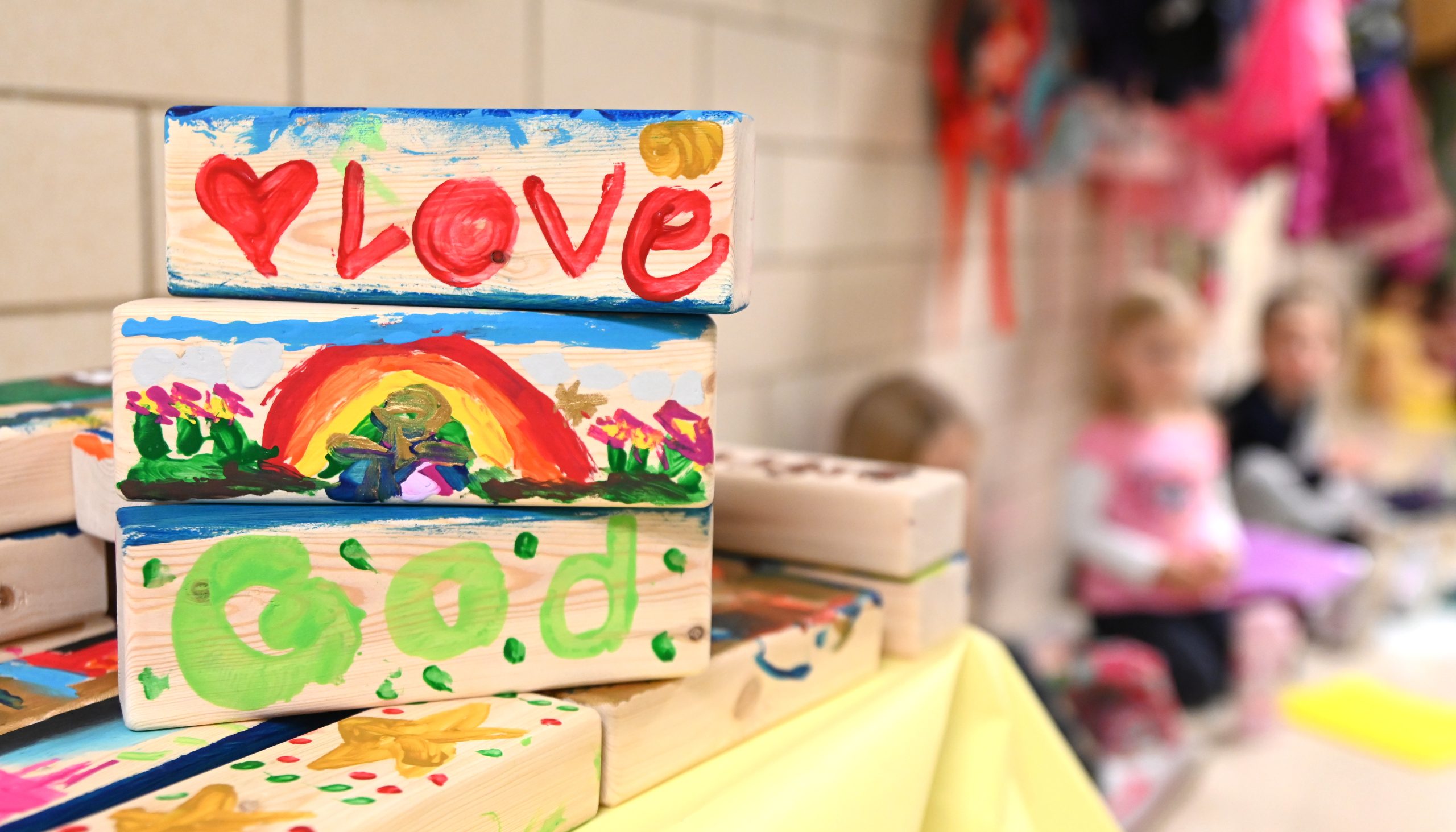 Wooden blocks painted with the words Love, God, and a rainbow scene.