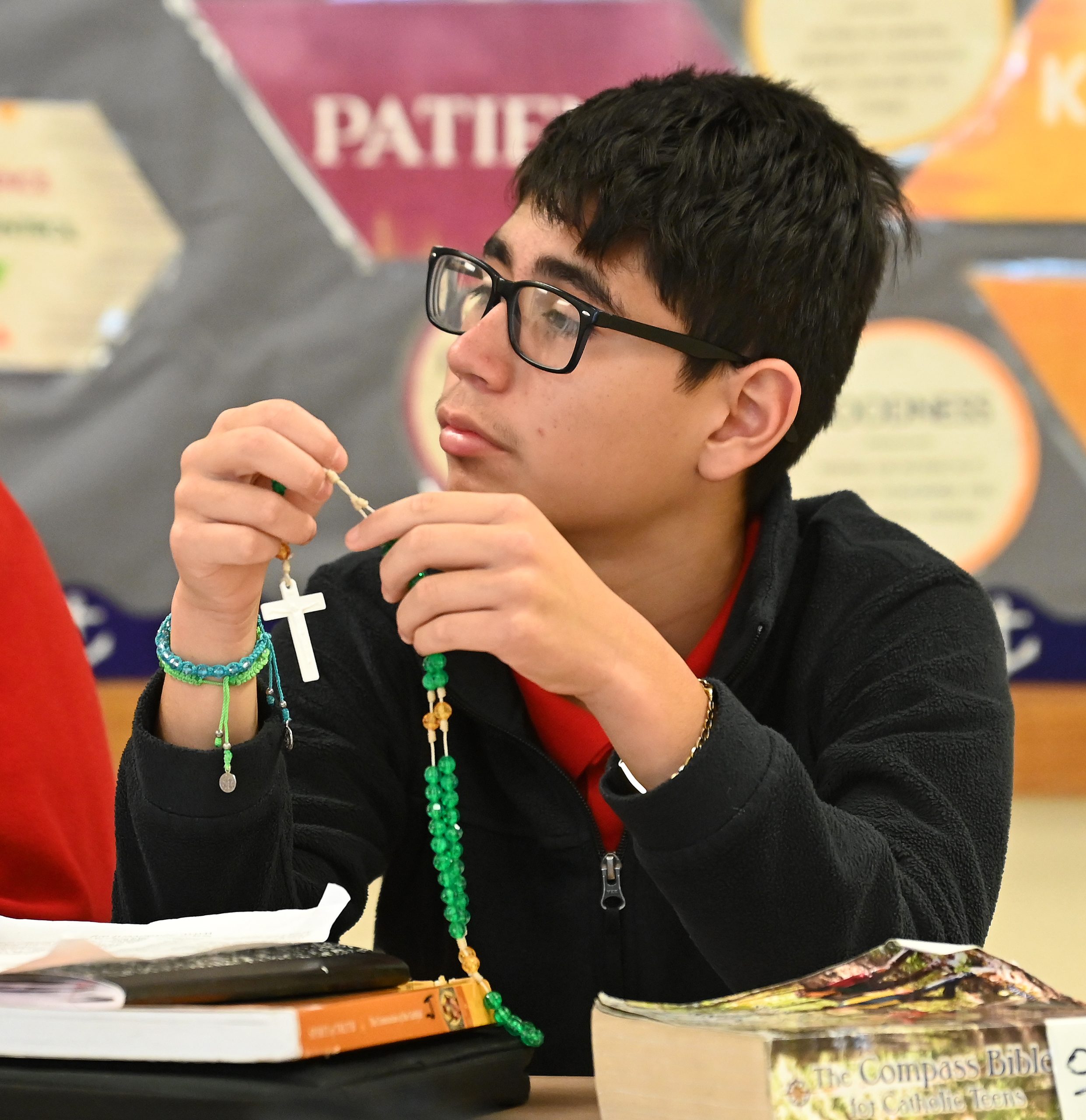 Student listens intently while holding a rosary.