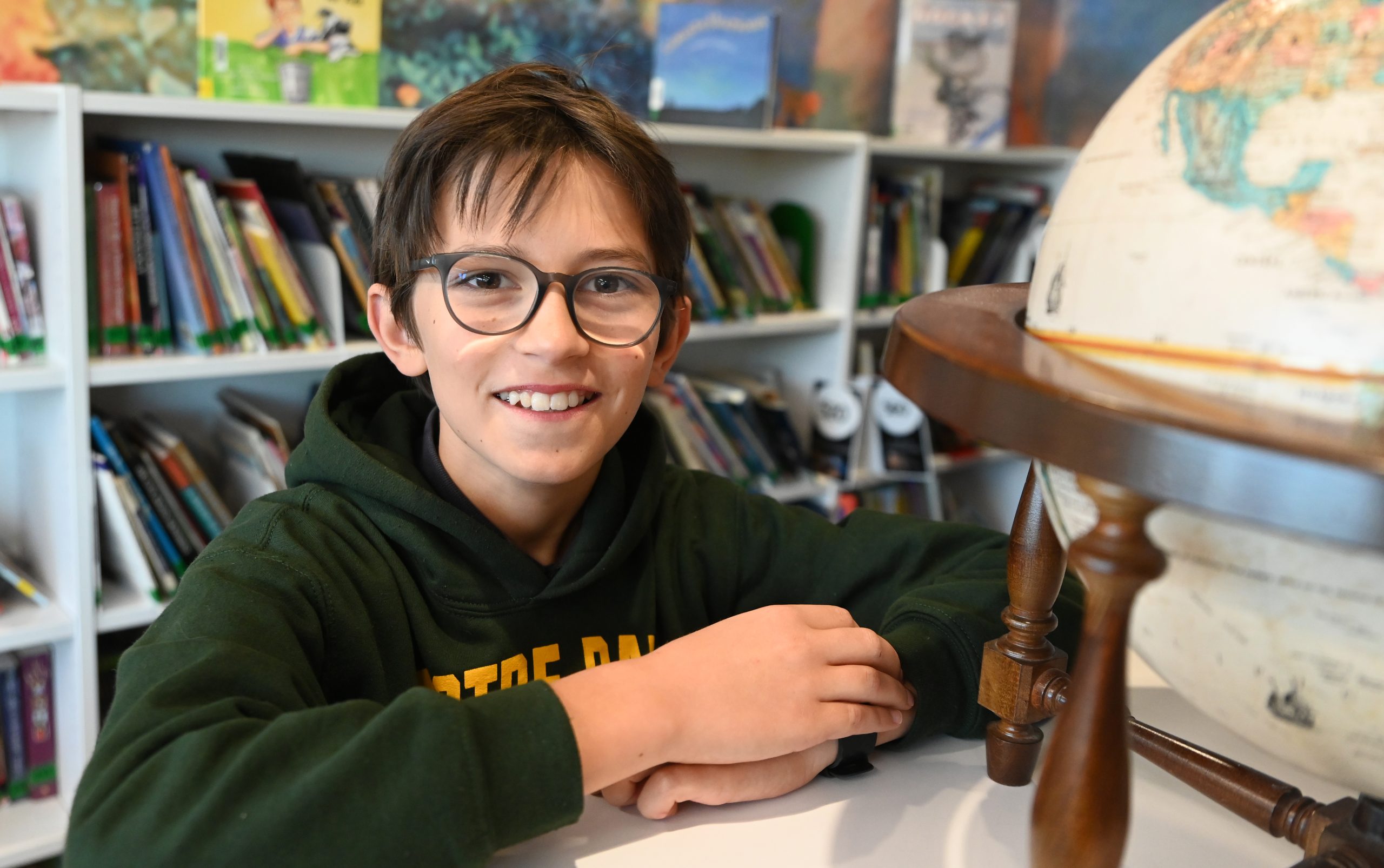 Notre Dame of De Pere student sits next to globe.