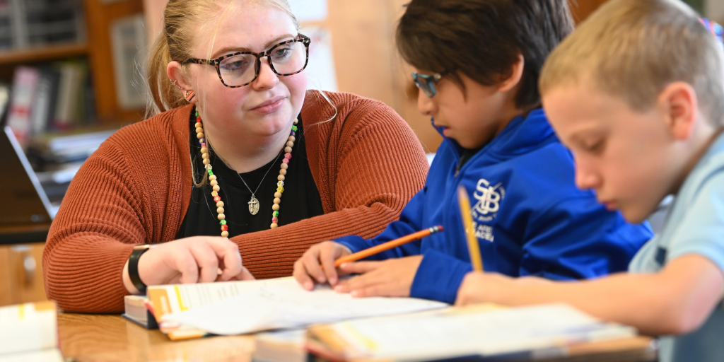 Staff working with students at table